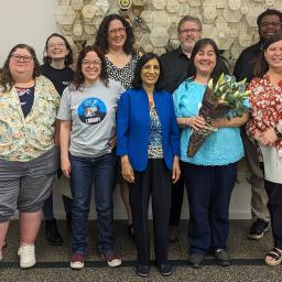 A group of Oak Park Public Library staff pose with a Triton College instructor in front of artwork at the Main Library