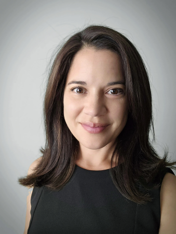 A headshot of Maggie Thomann against a gray background.