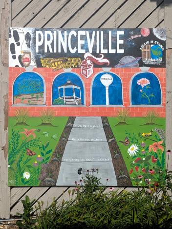 Princeville mural with Princeville across the top, picture windows with peonies, pumkins, the gazebo and water tower, and a sidewalk leading through the garden