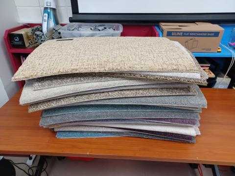 Stack of carpet sample squares in different colors.