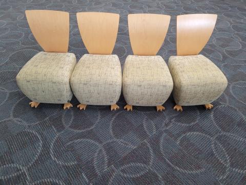 Four small chairs in a row, with wooden backs, cushioned seats, and small duck feet on the fronts