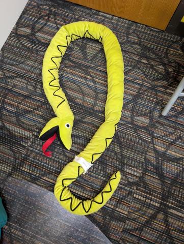 A green stuffed snake with a red tongue and zigzag patterns across its back.