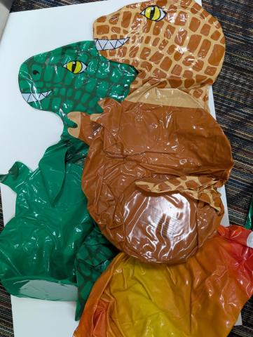 A green and sandy brown inflatable dinosaur, as well as a yellow inflatable planet or star.