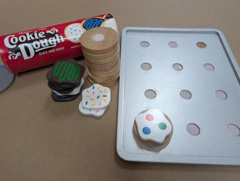 Wooden cookie toys, including a sheet pan and dough tube.