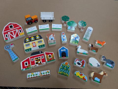 A collection of wooden farm animals, people, buildings, and plants.