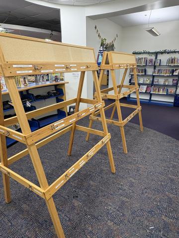 Wooden easels adorned with hooks intended to store backpacks, puppets, or other materials. 