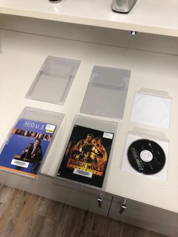 A clear multidisc sleeve, a clear dvd sleeve, a dvd pouch. A multidisc sleeve with Season One of House, a dvd sleeve with Jurassic World, a DVD pouch with the disc.