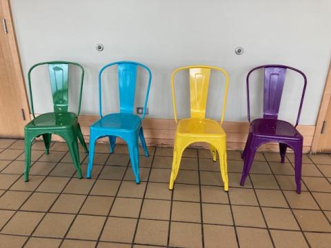 4 metal chairs: one green, one blue, one yellow, one purple.