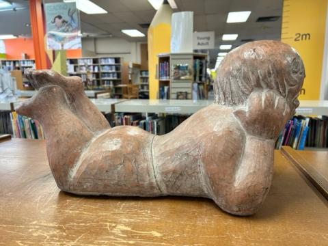 20 inch-long statue of child lying on stomach with their chin on their hands