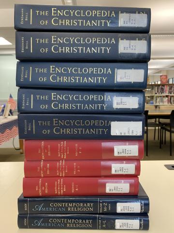 A stack of encyclopedia volumes on a desk.