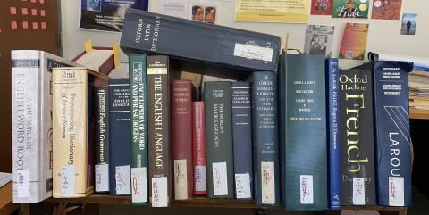 Row of dictionaries and thesauri on a book cart.