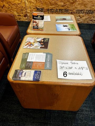 two laminate top cube shaped tables with paper flyers on them