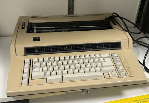 picture of beige electric typewriter on white shelf