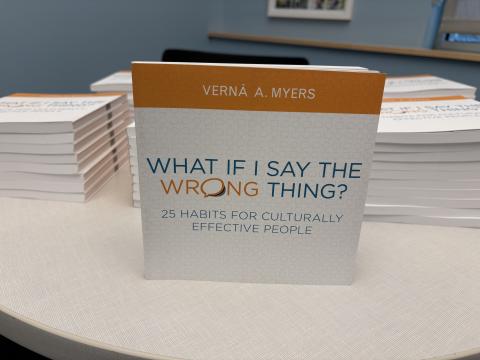 Pictures shows book What If I Say the Wrong Thing? by Vernā A. Myers with stacks of the same book behind it.