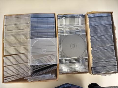 Several boxes with slim jewel cases for discs; two cases are on top of the boxes to show they have different color backs