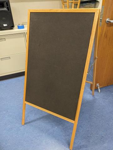 The felt side of an easel; the felt is dark gray with a wood frame.