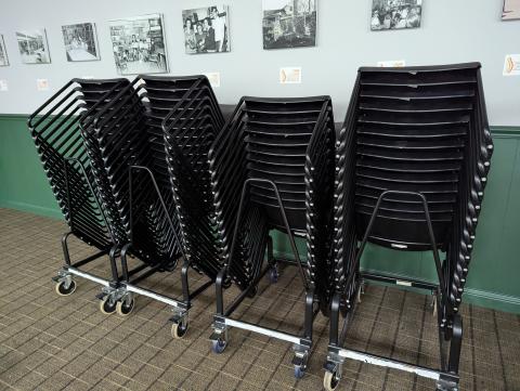 4 stacks of black chairs on rolling racks