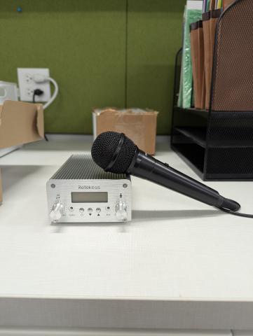 A silver FM transmitter with a black microphone