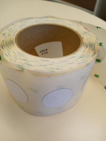 A partial roll of round RFID tags that fit around the center hub of a disc