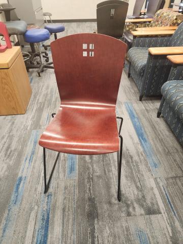 Wooden chair in dark red stain with square cutouts and metal sled base.