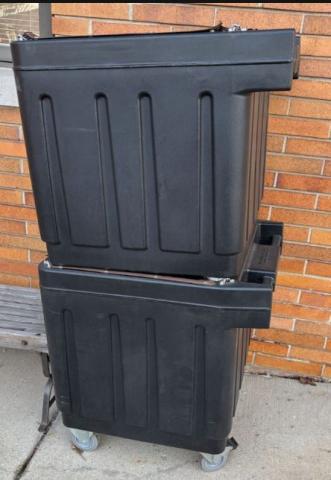 Two book drop bins stacked on top of each other outside against a brick wall.