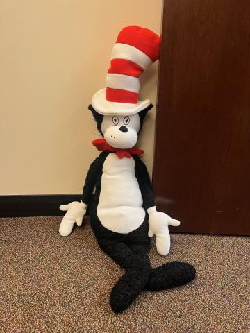 Black and white toy cat wearing a tall striped hat with a bow tie