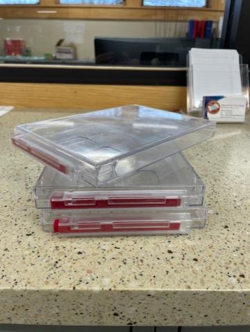 Clear plastic case with magnetic strip lock. Stable shelf storage to stand cases upright. 