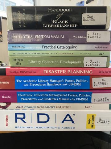 A stack of books on library work related topics and resources.