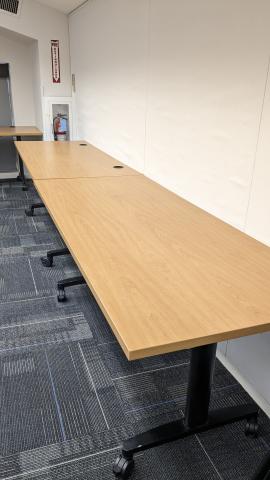 Two wood grain tables with black legs, one with grommets, one without