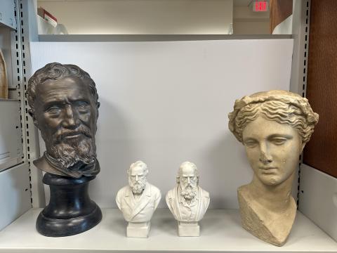 a dark bronze bust, two small white busts, and a sandstone bust