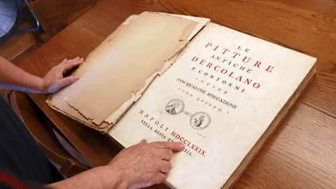 A finger points to the title page of a book written in Italian that indicates it was published in 1779.