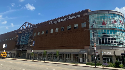 The front view of the outside of the Chicago History Museum, a building made of bricks, windows, and a metal scaffold.