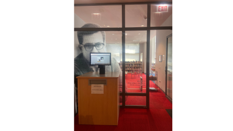 The doorway into the library. There's a book return to the left of the doorway with a computer monitor on top. 