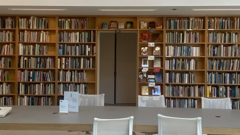 A table with chairs in front of library shelves.