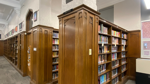 Rows of ornately detailed wooden bookshelves full of library books