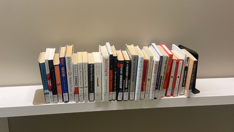 A white shelf holds various non-fiction, self help and information texts