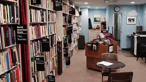 A room with walls painted like a blue sky. On the left, a floor to ceiling bookcase.  