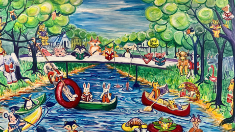 A colorful painted mural depicts many woodland creatures and other animals in various poses and activites reading books in and along the Leaf River. The scenery depicst the river with blue water, lined by brown banks that give way to grassy shores and tall trees with green leaves. 