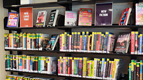 A wall lined with books labeled “new.” 