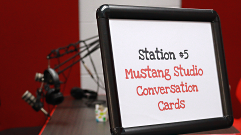 A sign that reads “Station 5: Mustang Studio Conversation Cards” in a podcast recording studio. 