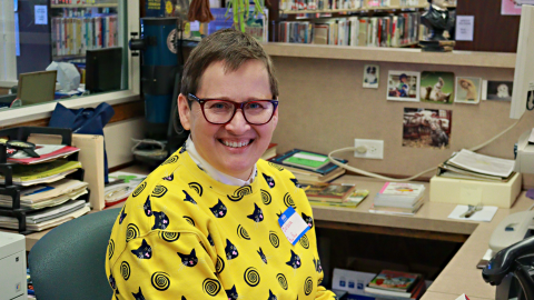 Barbara Zeman sits behind the circulation desk of the library. 