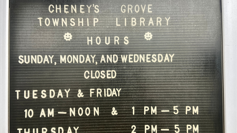 black and white letterboard sign displaying the name and hours of the Cheney's Grove Township Library.