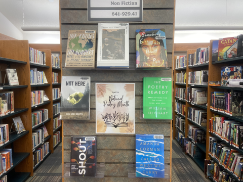 A National Poetry Month display featured on an endcap between aisles of bookshelves in the non-fiction section of the library.