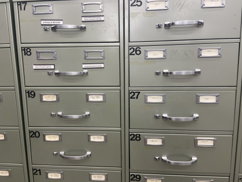 Grey metal storage drawers with brushed silver metal handles holding various journals.
