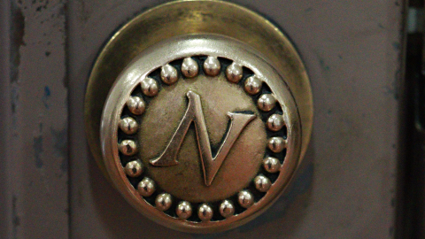 A metal doorknob embossed with the letter N.  