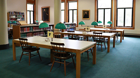Newberry Library study tables with green lamps in front of large windows. 