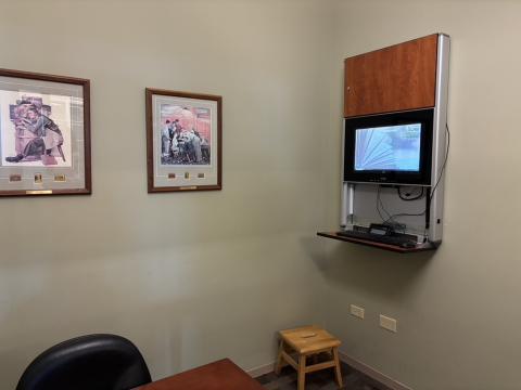 A wall-mounted mobile search station in the corner of a room is ready for use. On the wall two the left, two framed Norman Rockwell works hang on the beige wall. 