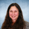 A headshot of Carolyn Sennett on a blue background.